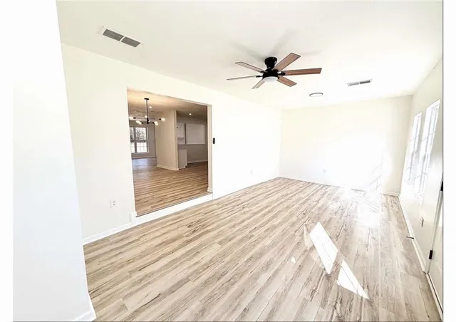 a view of a room with wooden floor and a ceiling fan