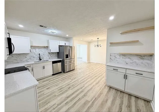 a kitchen with granite countertop white cabinets and white appliances
