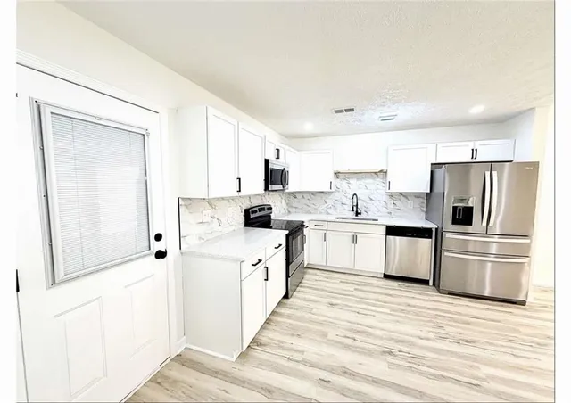 a kitchen with white cabinets and white appliances
