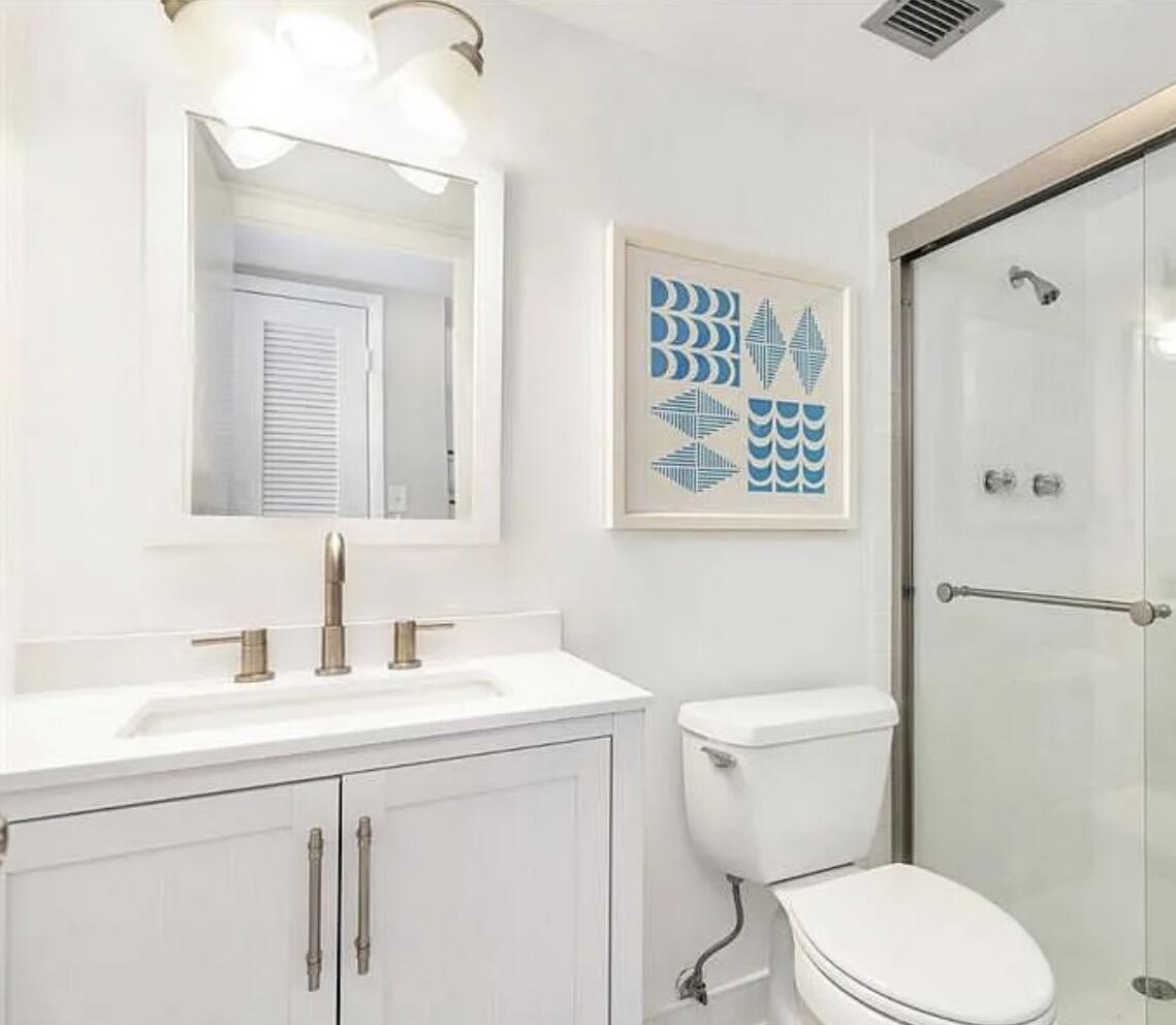 3800 Washington Road, Unit 310 West Palm Beach, FL 33405 - Photo 6 of 15 a bathroom with a toilet a sink a mirror and a shower