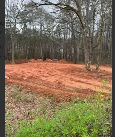 a backyard of a house with large trees and wooden fence