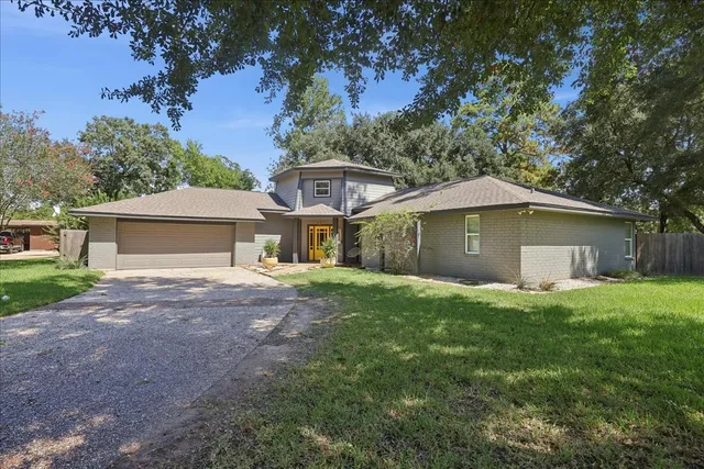 a view of a house with a yard and large tree