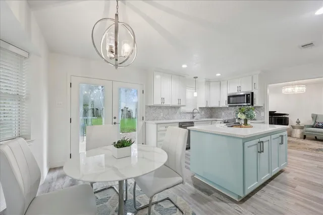 a kitchen with stainless steel appliances granite countertop a stove a sink a microwave a dining table and chairs with wooden floor