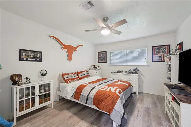 a bedroom with a bed a flat screen tv and dresser