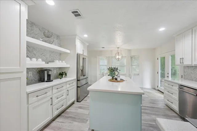 a large white kitchen with kitchen island white cabinets and stainless steel appliances