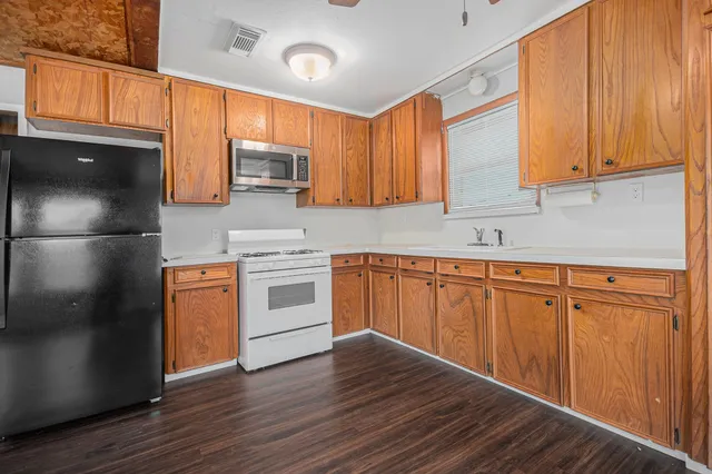 a kitchen with stainless steel appliances granite countertop a refrigerator a sink dishwasher and wooden cabinets with wooden floor