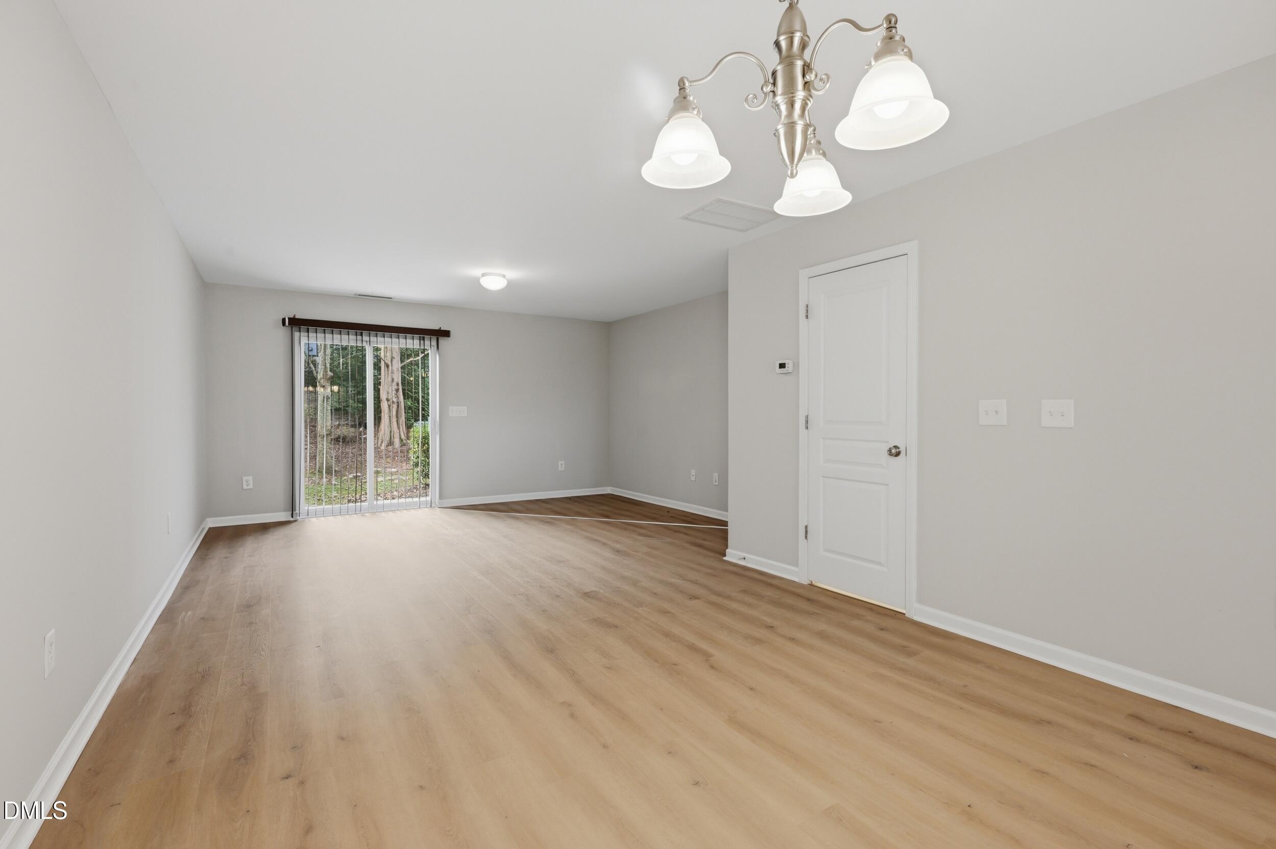 2907 Berkeley Springs Place Raleigh, NC 27616 - Photo 10 of 34 a view of an empty room with wooden floor and windows