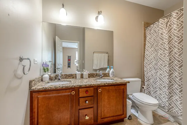 a bathroom with a granite countertop sink toilet and mirror