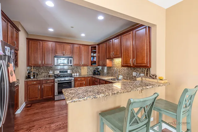 a kitchen with kitchen island granite countertop wooden cabinets and stainless steel appliances