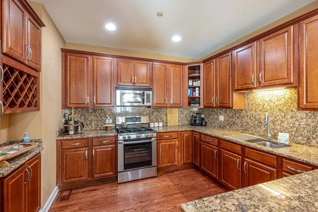 a kitchen with stainless steel appliances granite countertop wooden cabinets a sink and a stove