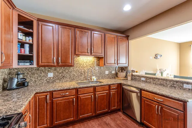 a kitchen with stainless steel appliances granite countertop wooden cabinets a sink and dishwasher with wooden floor