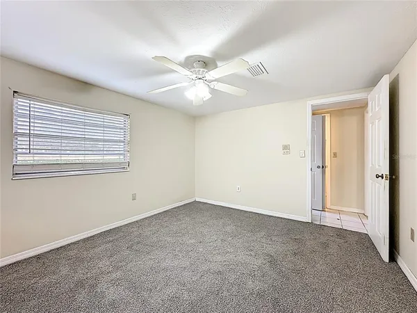 an empty room with windows and fan