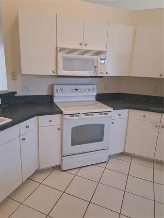 a kitchen with granite countertop white cabinets and white appliances