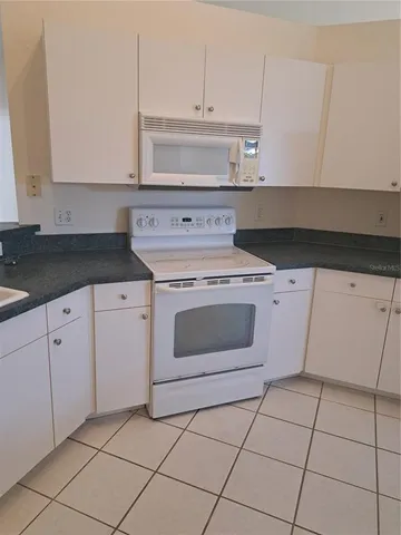 a kitchen with granite countertop white cabinets and white appliances
