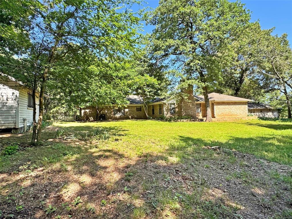 3870 County Road Arthur City, TX 75411 - Photo 5 of 39 Expansive grassy yard with mature trees and a brick exterior residence featuring a prominent chimney structure