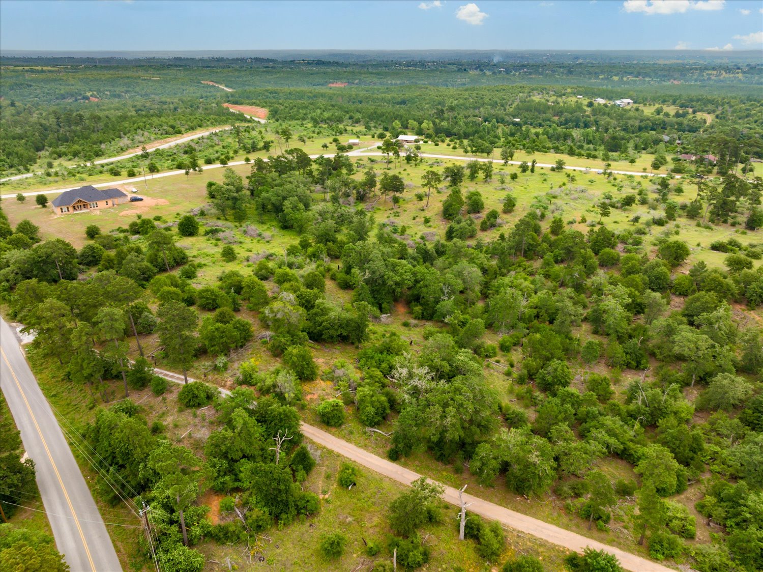 0 McAllister Road Bastrop, TX 78602 - Photo 10 of 12 A sweeping aerial view reveals a vast expanse of lush, green landscape with scattered homes and winding roads.