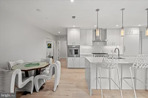 a kitchen with kitchen island granite countertop lots of white cabinets and stainless steel appliances