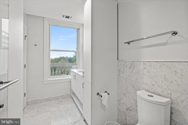 a bathroom with a granite countertop sink a toilet and shower
