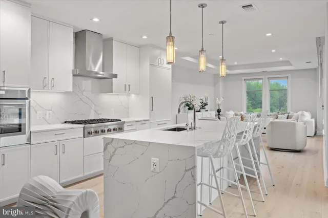 a kitchen with stainless steel appliances granite countertop a sink a stove a dining table and chairs