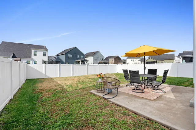 a view of a patio with chairs and table under an umbrella with wooden fence