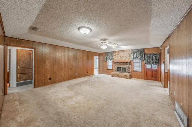 a view of an empty room with wooden floor kitchen view and a window