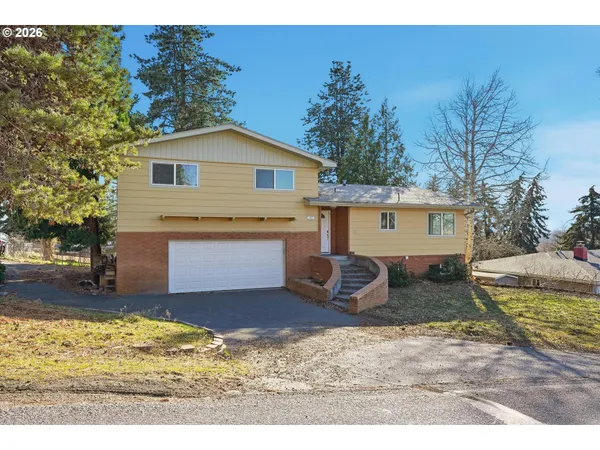 a view of a white house next to a yard with big trees