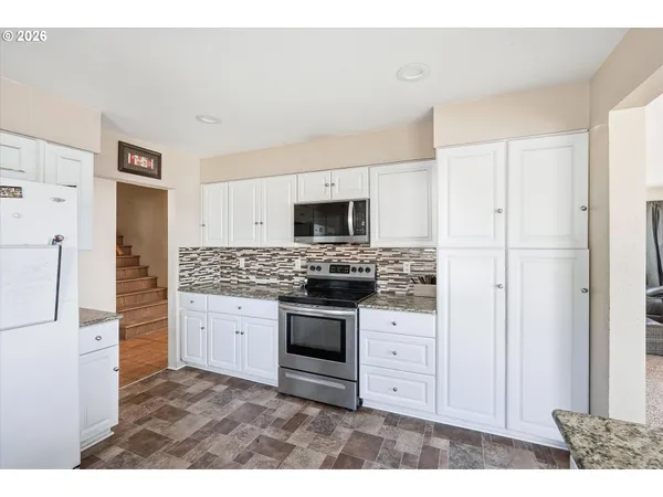 a kitchen with stainless steel appliances kitchen island granite countertop a refrigerator stove and oven