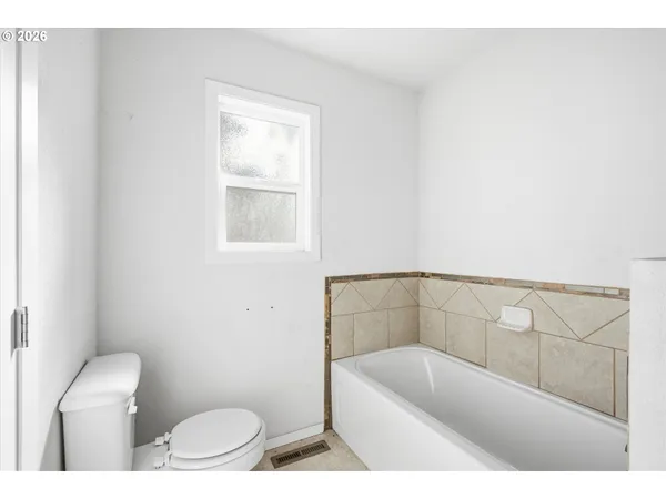 a bathroom with a bathtub a window a toilet and a bathtub