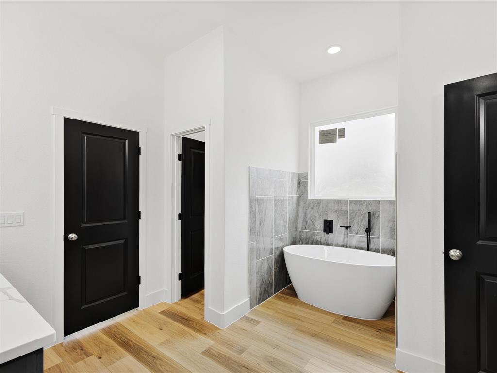 544 Shepherd Road Combine, TX 75159 - Photo 22 of 36 Bathroom featuring tile walls, a soaking tub, light wood-type flooring, vanity, and a wainscoted wall