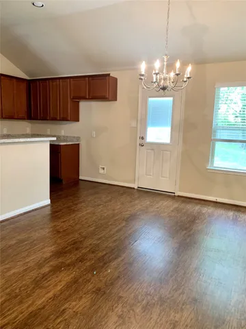 a kitchen with granite countertop wooden floors a sink cabinets and a chandelier