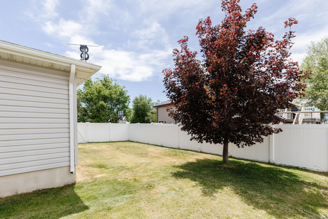 1145 West 2640th Street South Logan, UT 84321 - Photo 15 of 17 Expansive backyard featuring a manicured lawn, a mature red-leafed tree, and a white privacy fence