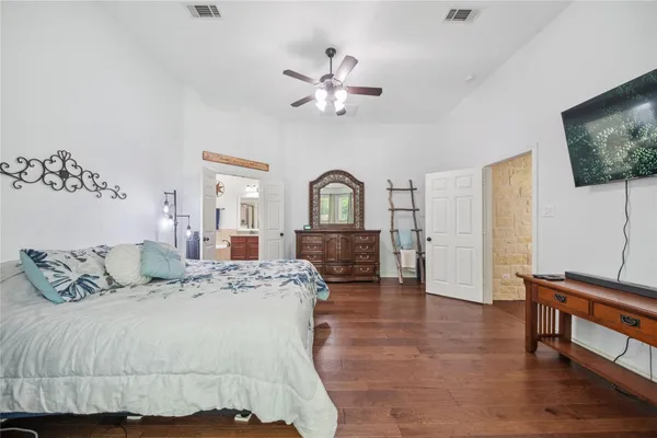 a spacious bedroom with a bed a dresser and flat screen tv