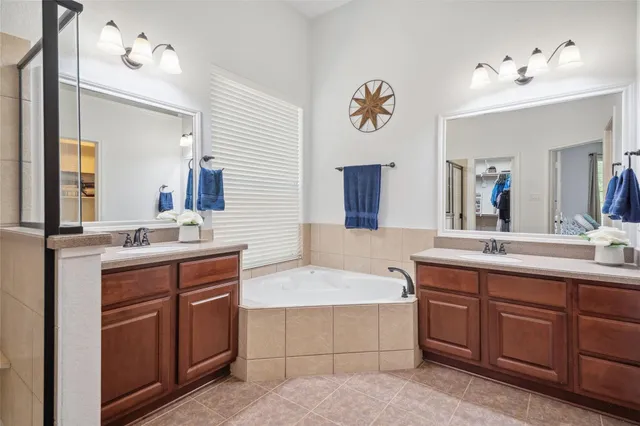 a bathroom with a tub double vanity sink and mirror