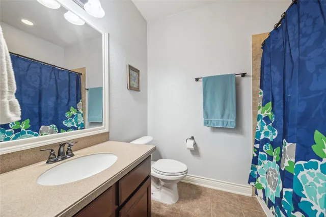 a bathroom with a granite countertop toilet a sink and a mirror