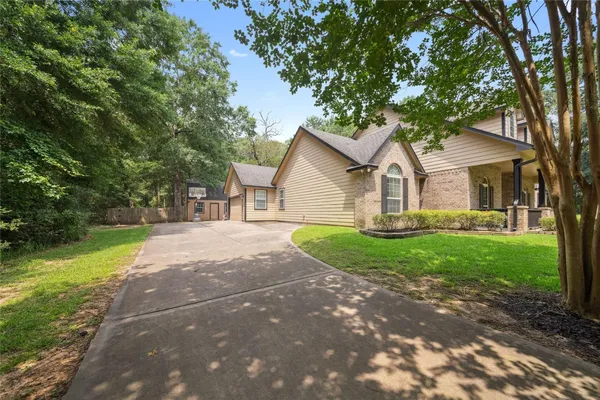 a view of a yard in front of a house with large trees