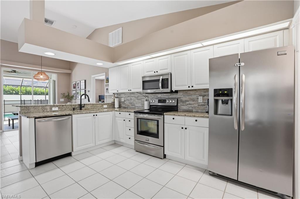4356 Mistlethrush Lane Naples, FL 34119 - Photo 11 of 38 a kitchen with white cabinets stainless steel appliances and a window