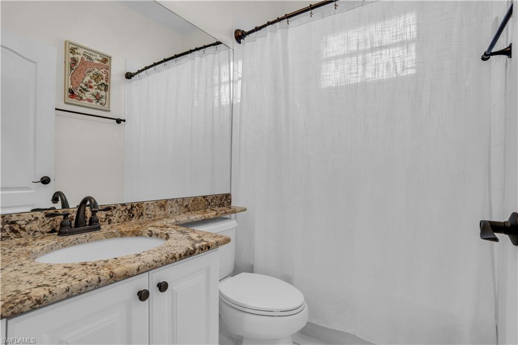 4356 Mistlethrush Lane Naples, FL 34119 - Photo 20 of 38 a bathroom with a granite countertop sink a toilet and a mirror