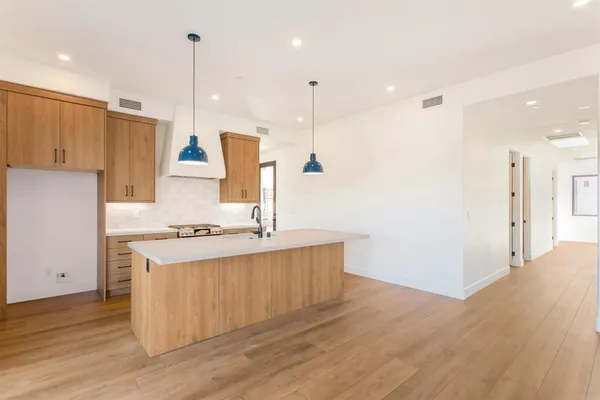 a kitchen with kitchen island a stove a refrigerator a sink and a oven with wooden floor