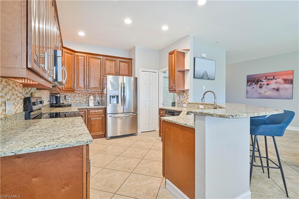 238 Stanhope Circle Naples, FL 34104 - Photo 15 of 33 a kitchen with stainless steel appliances granite countertop a refrigerator sink and wooden cabinets