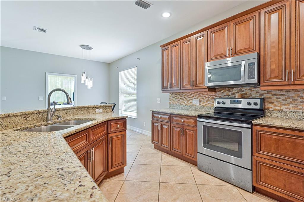238 Stanhope Circle Naples, FL 34104 - Photo 18 of 33 a kitchen with stainless steel appliances granite countertop a stove sink and cabinets