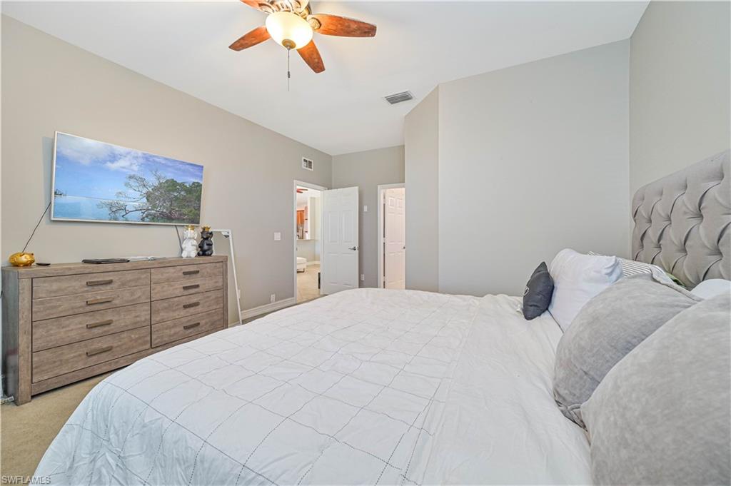 238 Stanhope Circle Naples, FL 34104 - Photo 24 of 33 a bedroom with a large bed and a flat tv screen on dresser