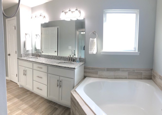 204 Goshen Road Lebanon, TN 37087 - Photo 9 of 24 a bathroom with a tub a double vanity sink and a large mirror