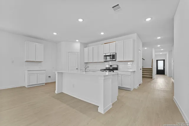 a large white kitchen with white cabinets and stainless steel appliances