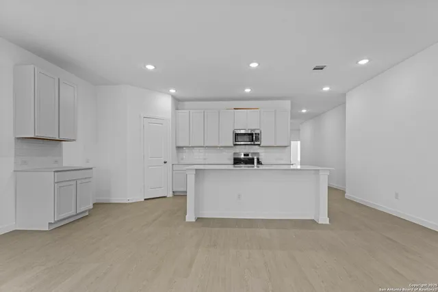 a view of kitchen with stainless steel appliances refrigerator stove microwave and cabinets