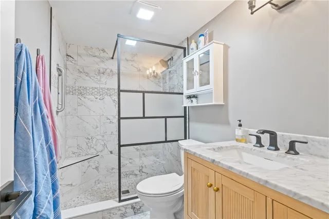 a bathroom with a granite countertop sink toilet and shower