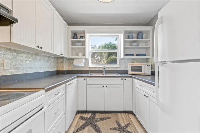 a kitchen with granite countertop white cabinets and white appliances