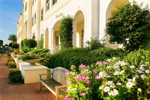 a front view of a multi story residential apartment building with yard and flowers