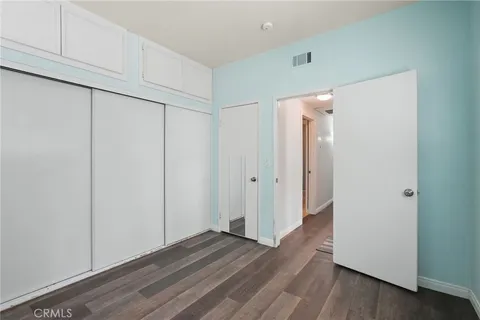 a view of an empty room with closet and wooden floor