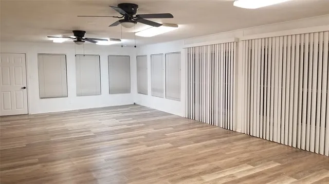 en empty room with wooden floor fan and windows