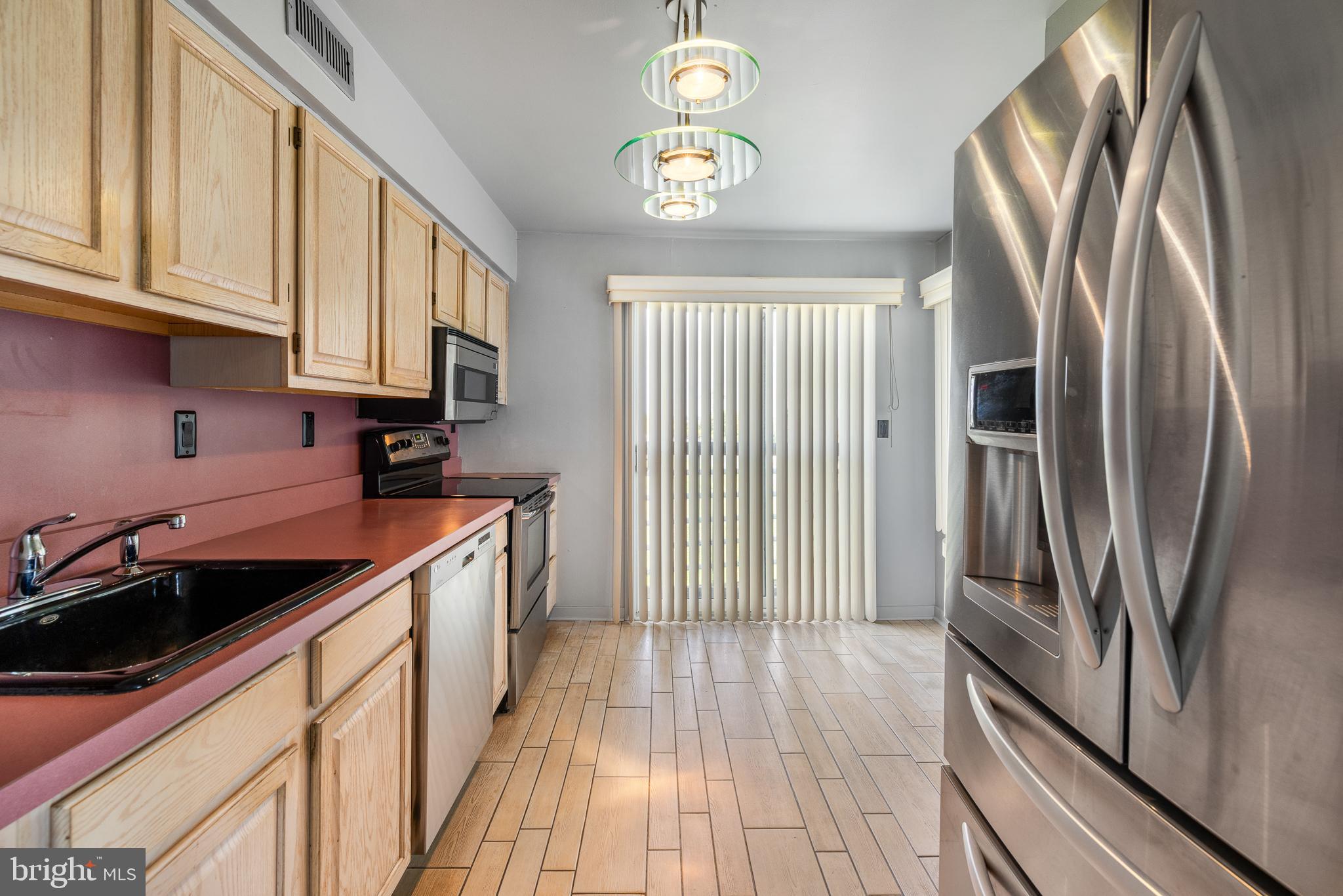 5213 Le Parc Drive, Unit 4 Wilmington, DE 19809 - Photo 21 of 37 a kitchen with stainless steel appliances granite countertop a refrigerator a sink dishwasher a stove and a dining table with wooden floor